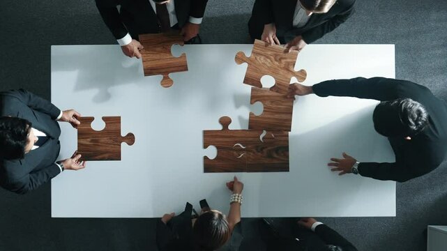 Top view of business people putting jigsaw together at meeting room. Professional marketing team standing at table while gathering puzzle piece. Show unity, cooperation and team working. Directorate.
