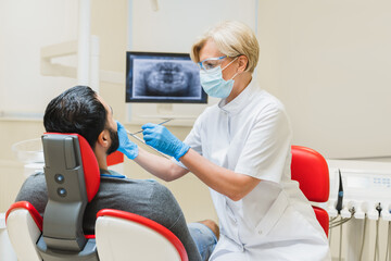 Stomatologist dentist orthodontist curing operating patient`s mouth cavity while checking up x-ray...