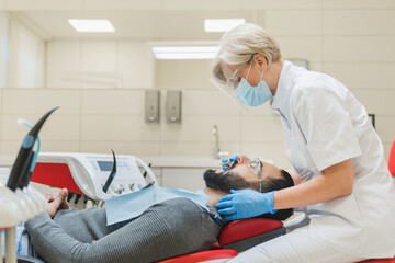 Side view photo of female dentist orthodontist curing healing operating filling tooth mouth cavity...