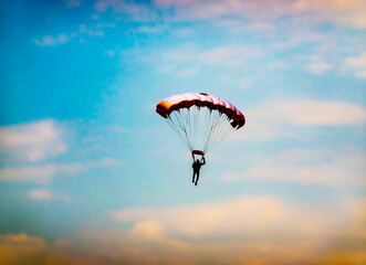 A skydiver with an open parachute heading towards a designated target on the ground