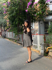 Brunette, beautiful, young girl smiling with a happy expression. Girl posing from the side and full length outdoors, on a street. Flirty, cute playful girl