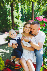 Two parents are playing on a walk with their toddler son. A young married couple, a man, a woman and a little son, are walking in the park. Time for a walk, mom, dad and small child.