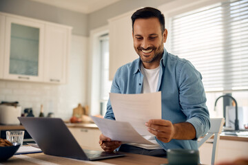 Happy entrepreneur analyzing business reports while working at home.