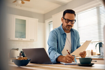 Mid adult man taking notes while going through home finances.