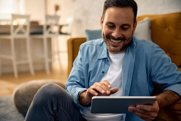 Happy man using touchpad while relaxing at home.