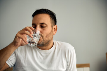 Thirsty man having  glass of water before bedtime.