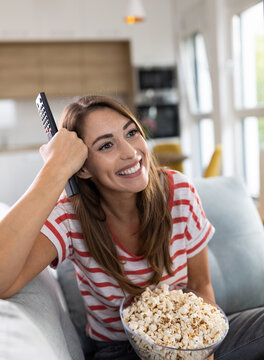 Woman enjoying watching tv and eating popcorn in living room