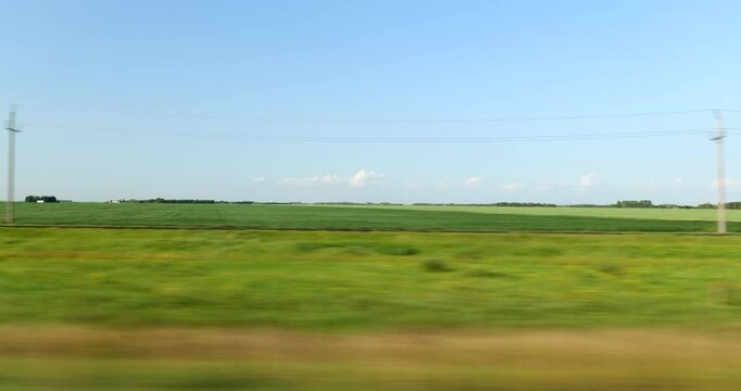 Driving plate side view on a highway through open plains and farmland in Midwestern United States agricultural fields under a wide sky rural travel and American heartland concept