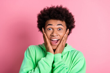 Photo of nice young man arms touch cheekbones wear green hoodie isolared on pink color background