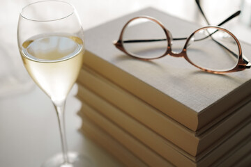 Glasses on top of a stack of books and a glass of white wine