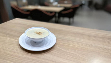 Mushroom soup served in a white bowl on a wooden table at a restaurant. Creamy mushroom soup in a white bowl sits on a wooden table at a restaurant.