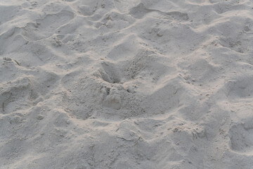 A sandy surface with an uneven wavy texture, created by the wind and tourists who love building sandcastles.