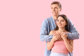 Happy young couple hugging on pink background