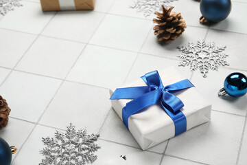 Christmas gift box with snowflakes and cone on white tile background