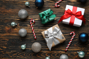 Christmas balls with gift boxes and candy canes on wooden background