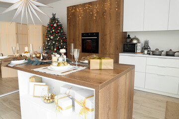 Christmas setting with burning candles on dining table in kitchen