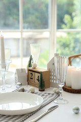 Festive table setting with burning candles and Christmas decor