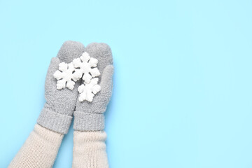 Female hands in warm mittens with beautiful Christmas decorations on color background, closeup