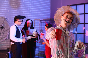 Fototapeta premium Young man in costume with drink at Halloween party