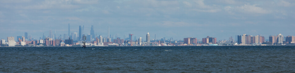 Obraz premium New York City is seen across the water from Sandy Hook, New Jersey. Brooklyn, including the famous Coney Island, can be seen in the front, with Manhattan Island behind.