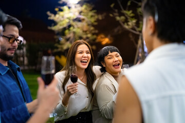 Group of Happy Asian millennial generation people friends enjoy and fun celebration reunion meeting outdoor dinner party with drinking wine and dancing in the garden at restaurant on holiday vacation.