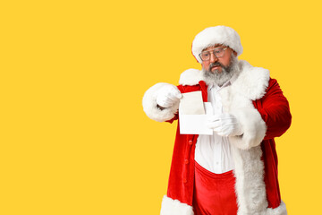 Santa Claus reading letter on yellow background