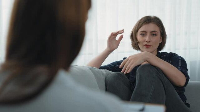 Sad PTSD woman patient in therapy for mental health with psychologist, depression or grief after life failure. Frustrated trauma young woman talking to prim psychologist about emotion in clinic