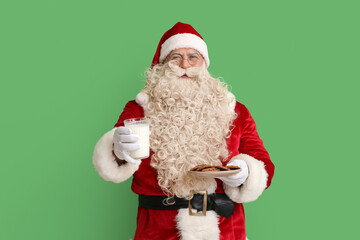 Santa Claus with glass of milk and tasty cookies on green background