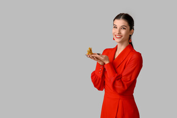 Beautiful young happy woman with golden dragon figurine on grey background. Chinese New Year celebration