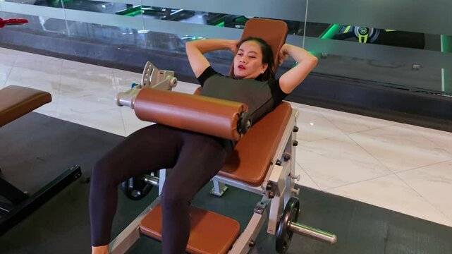 A beautiful asian woman in her 40s doing hip thrust exercises, wearing sportswear and in good physical condition. The view is from the sid