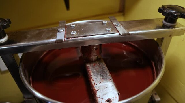 Close up view of rich, liquid chocolate being conched in an artisan factory, highlighting the smooth texture and intricate machinery involved in chocolate production. Selective focus