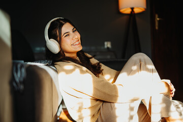 Young caucasian woman enjoying music on wireless headphones at home