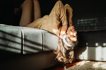 Young caucasian woman enjoying music on wireless headphones at home