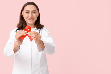 Female doctor with red ribbon on pink background. World AIDS Day concept