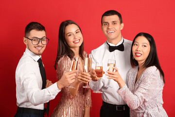 Group of friends with champagne on red background. New Year celebration