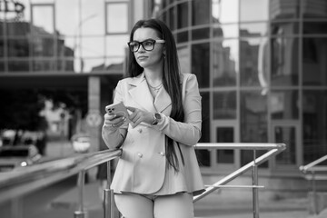 Elegantly Dressed Businesswoman Engaged with Her Smartphone in Urban Setting