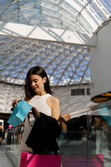 Shopping lady is opening her present in shopping mall. Woman is looking through her bargains after sales on Black Friday. Surprising girl with jewelry gift for her birthday.