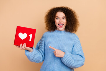 Photo portrait of young blogger excited girl promoting her social media holding red button subscription isolated on beige color background