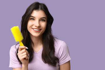 Beautiful young woman with yellow hair brush on lilac background