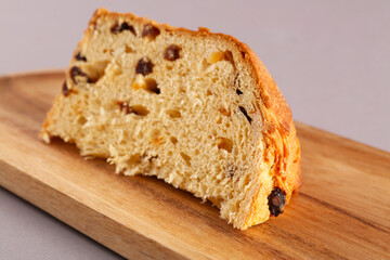 Wooden tray with piece of Panettone on grey background