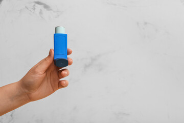 Female hand with modern asthma inhaler on white grunge background