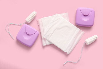 Menstrual pads with tampons and storage boxes on pink background © Pixel-Shot