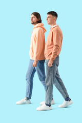 Young men in white sneakers walking on blue background