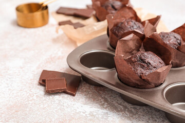Baking mold with tasty chocolate muffins on white grunge background