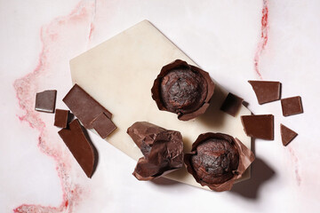 Board with tasty chocolate muffins on white marble background