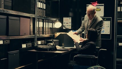 Forensic team conducting private investigation with case files, studying classified records in...