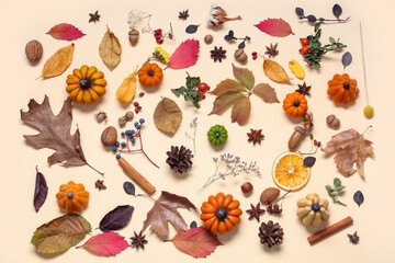 Candles in shape of pumpkin, autumn leaves and berries on beige background