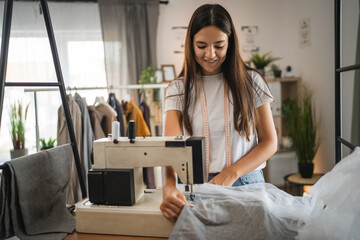 Adult woman tailor or fashion designer stand and work on sewing machine