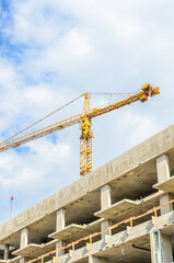 High-rise building under construction. The site with cranes against blue sky