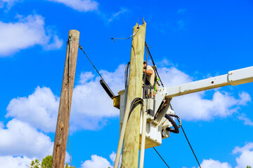 Electrician working on electric power system after hurricane using hydraulic tower mounted bucket...